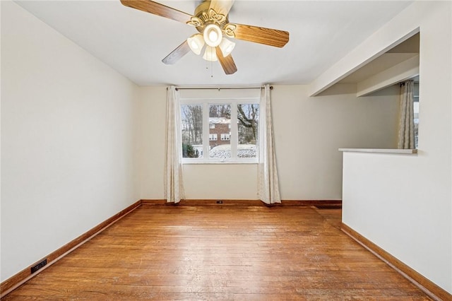 unfurnished room with wood-type flooring, visible vents, baseboards, and ceiling fan