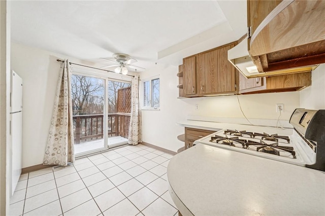 kitchen featuring baseboards, a ceiling fan, freestanding refrigerator, light countertops, and light tile patterned flooring