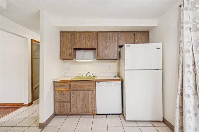 kitchen with white appliances, light tile patterned floors, light countertops, and a sink