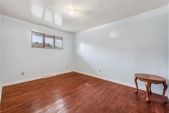 unfurnished room featuring visible vents, dark wood finished floors, and baseboards