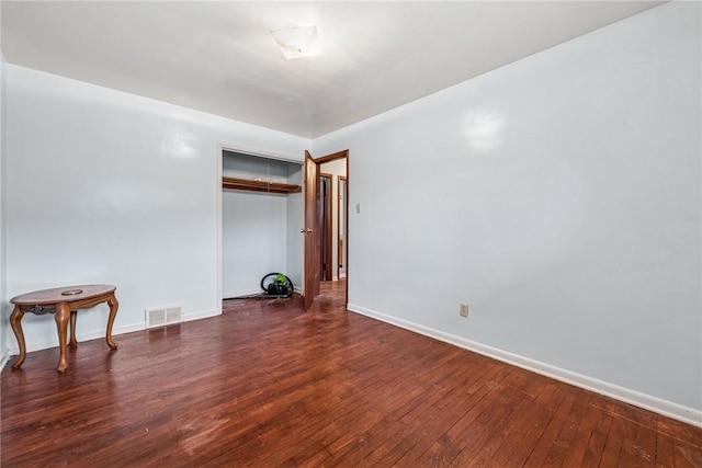 empty room with visible vents, baseboards, and hardwood / wood-style flooring