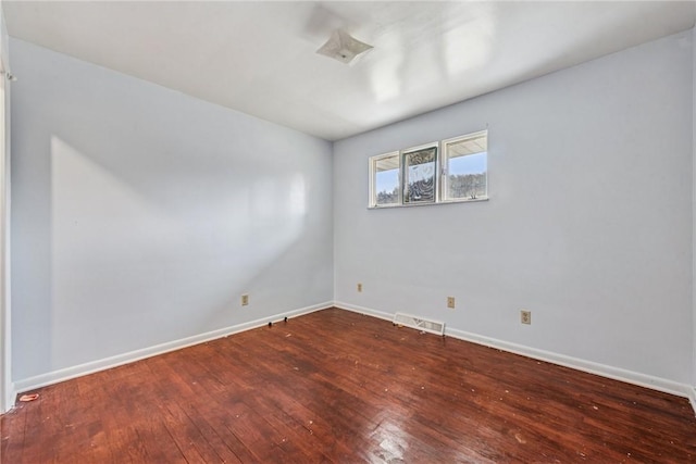 empty room with hardwood / wood-style floors, visible vents, and baseboards