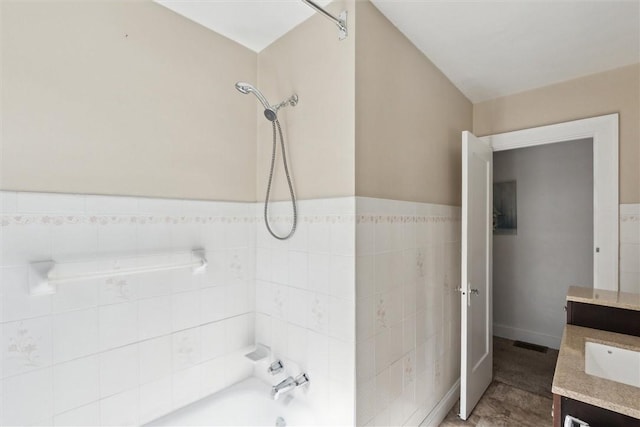 full bathroom with tile walls, visible vents, shower / bath combination, and vanity