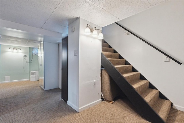 staircase featuring a paneled ceiling, carpet flooring, and baseboards