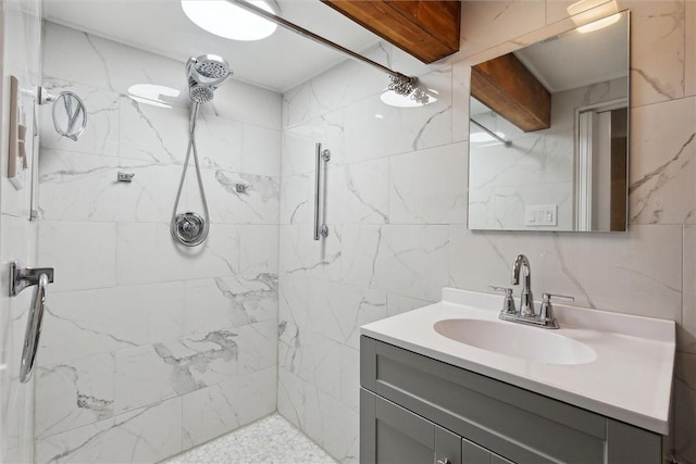 bathroom with a marble finish shower, vanity, and tile walls