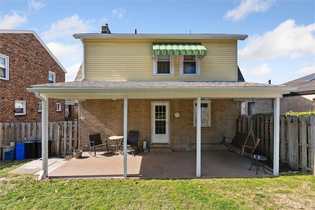 rear view of house with a yard, a patio area, brick siding, and fence