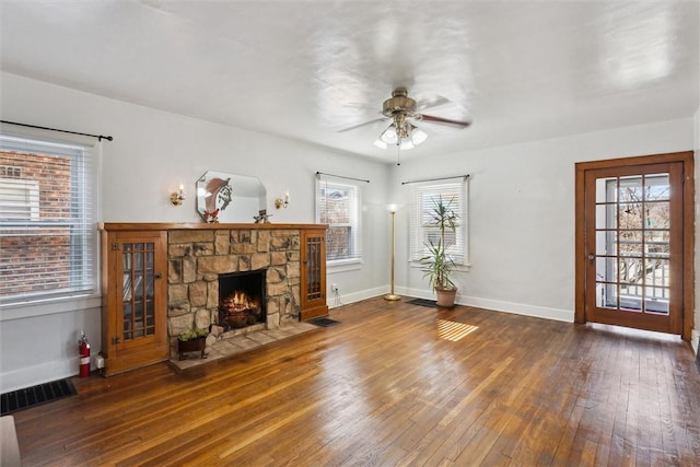 unfurnished living room featuring baseboards, visible vents, a ceiling fan, hardwood / wood-style floors, and a fireplace