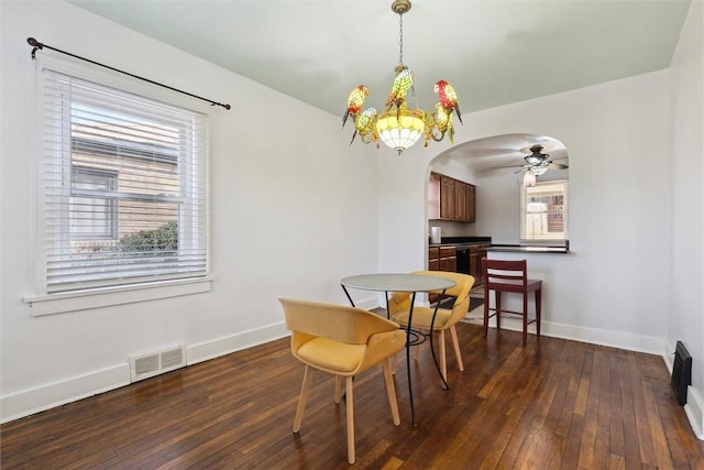 dining room featuring arched walkways, dark wood-style floors, visible vents, and baseboards