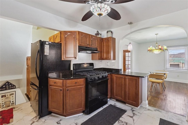 kitchen with arched walkways, marble finish floor, a peninsula, under cabinet range hood, and black appliances