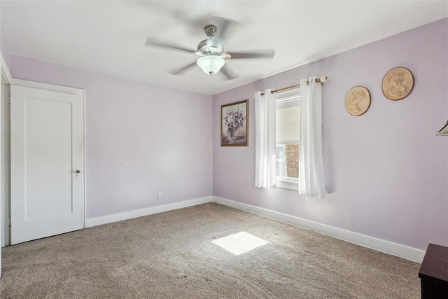 carpeted spare room with ceiling fan and baseboards