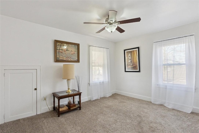 interior space with a ceiling fan, light colored carpet, and baseboards