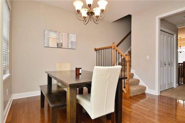 dining space featuring baseboards, wood finished floors, stairs, and an inviting chandelier