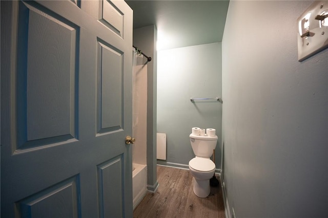 bathroom with shower / bath combination with curtain, wood finished floors, toilet, and baseboards