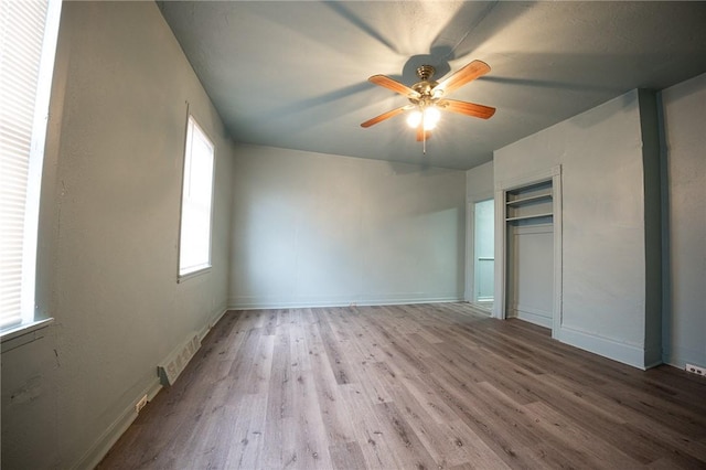 unfurnished bedroom with a ceiling fan, visible vents, baseboards, and wood finished floors