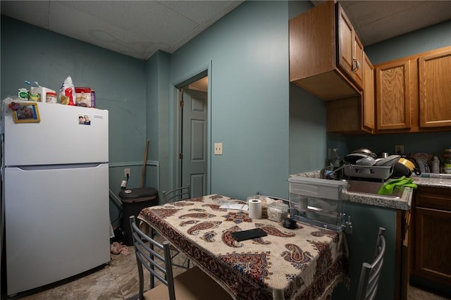 kitchen with brown cabinets and freestanding refrigerator