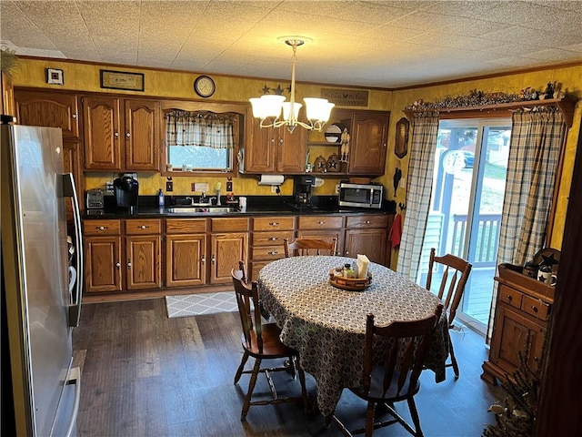 kitchen featuring a notable chandelier, dark countertops, appliances with stainless steel finishes, dark wood-type flooring, and a sink