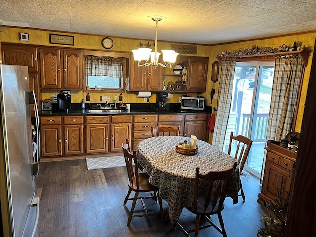 kitchen featuring stainless steel appliances, a sink, dark wood-style floors, brown cabinetry, and dark countertops