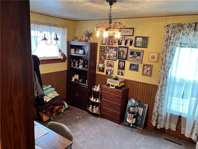 living area with visible vents, wainscoting, wooden walls, and carpet flooring