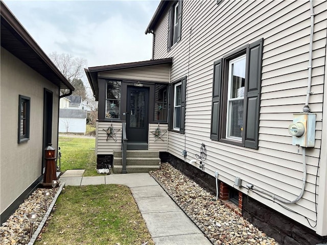 view of side of home with entry steps, a sunroom, and a lawn