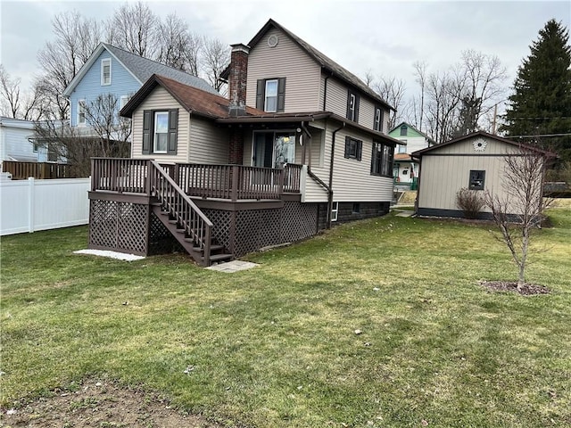 rear view of property featuring a chimney, fence, a lawn, and a wooden deck