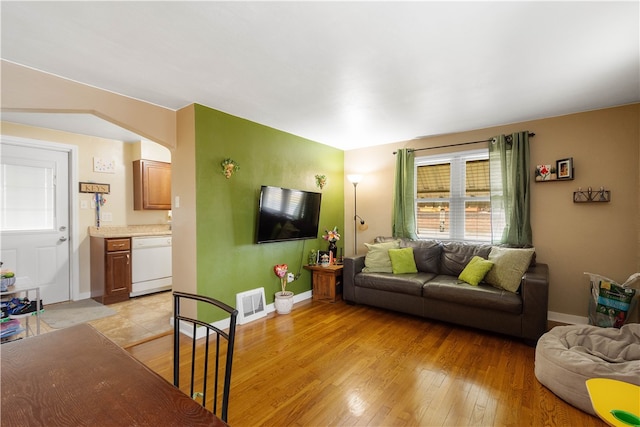 living room with light wood-type flooring, visible vents, arched walkways, and baseboards