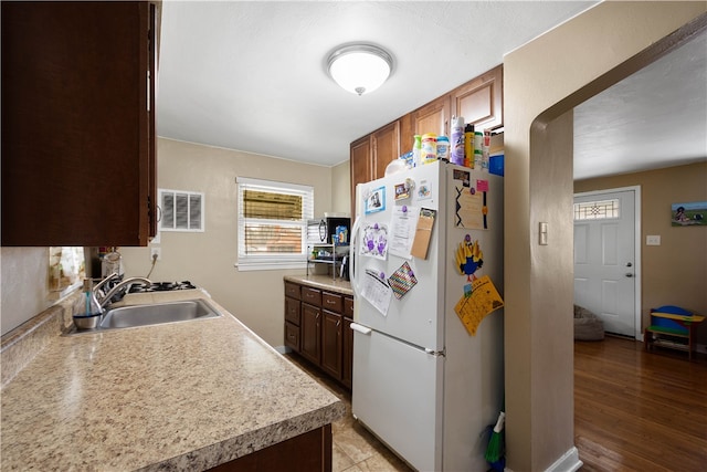 kitchen with light wood finished floors, light countertops, visible vents, freestanding refrigerator, and a sink