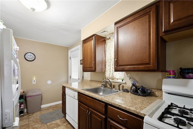 kitchen featuring light countertops, white appliances, a sink, and baseboards