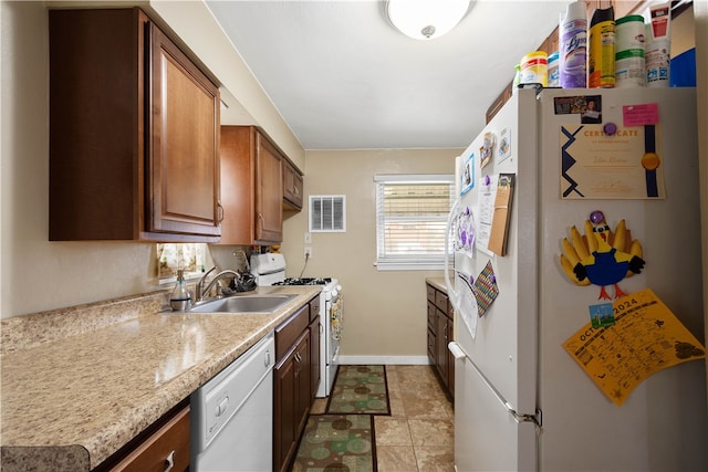 kitchen with light countertops, visible vents, a sink, white appliances, and baseboards