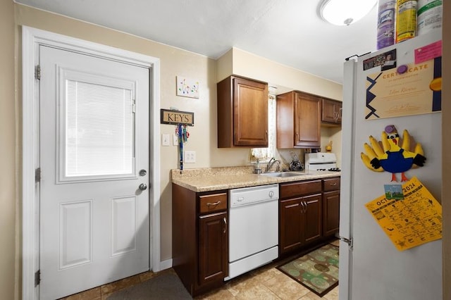 kitchen with light countertops, white appliances, and a sink