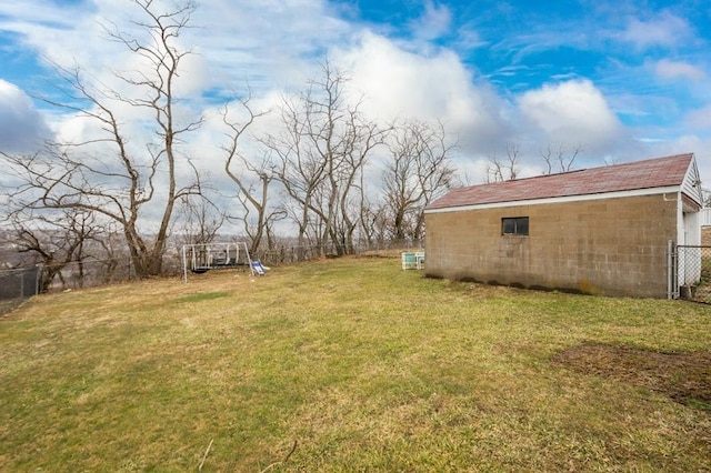 view of yard featuring an outbuilding, a playground, and fence