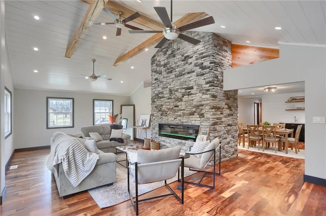 living room with crown molding, a fireplace, baseboards, and wood finished floors