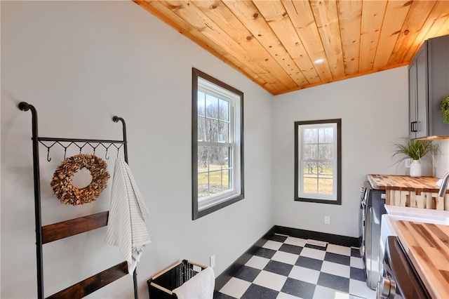 clothes washing area with laundry area, baseboards, wooden ceiling, dark floors, and independent washer and dryer