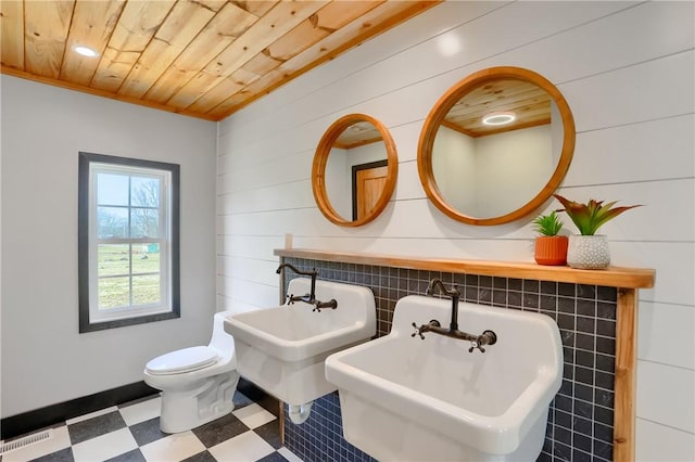 bathroom featuring wooden ceiling, toilet, a sink, visible vents, and tile patterned floors