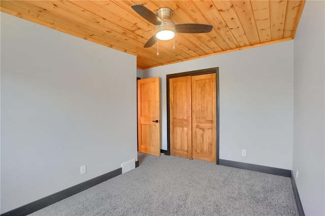 unfurnished bedroom featuring carpet floors, wood ceiling, baseboards, a closet, and crown molding