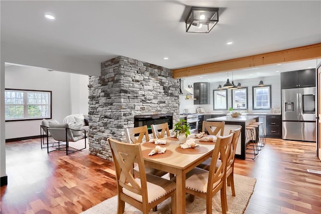 dining area with recessed lighting, baseboards, a stone fireplace, and light wood finished floors