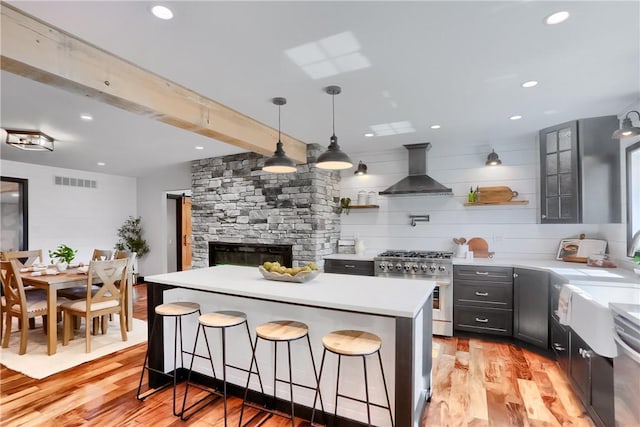 kitchen featuring open shelves, light countertops, visible vents, high end range, and wall chimney exhaust hood