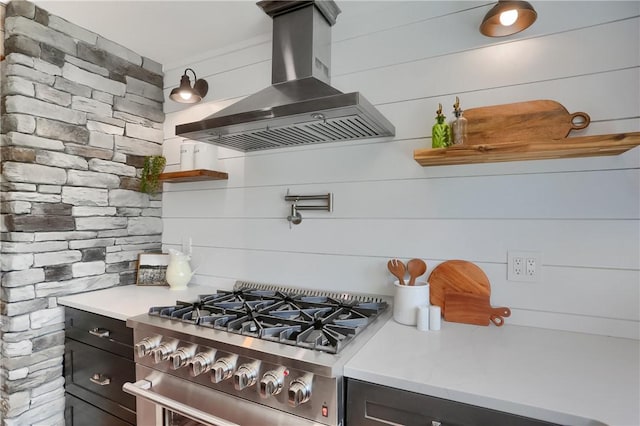 kitchen featuring stainless steel stove, light countertops, wall chimney exhaust hood, and open shelves