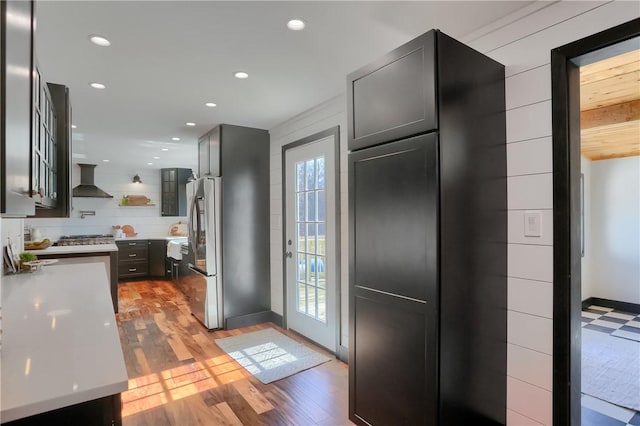 kitchen featuring open shelves, light countertops, freestanding refrigerator, light wood-type flooring, and wall chimney exhaust hood