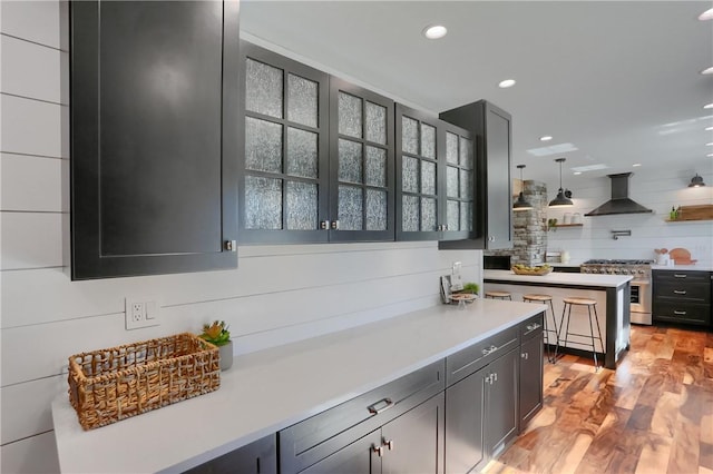 kitchen with light countertops, ventilation hood, high end stainless steel range, and light wood-style floors