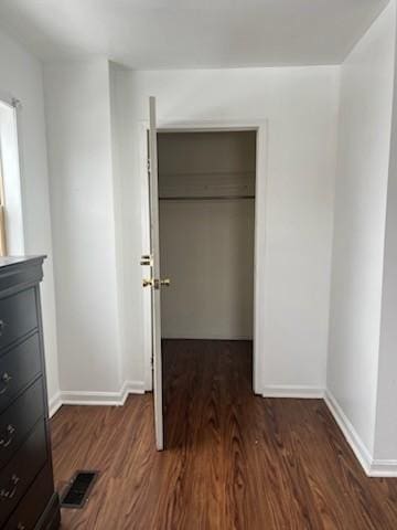 unfurnished bedroom with baseboards, a closet, visible vents, and wood finished floors