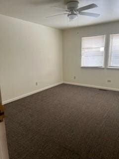 empty room with ceiling fan, dark carpet, and baseboards