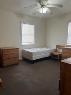 bedroom featuring dark colored carpet, multiple windows, and a ceiling fan