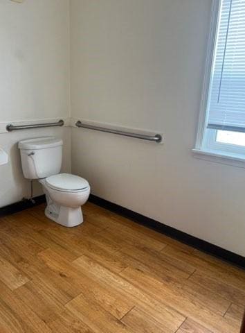 bathroom with wood finished floors, toilet, and baseboards