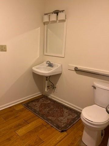 bathroom with toilet, baseboards, and wood finished floors