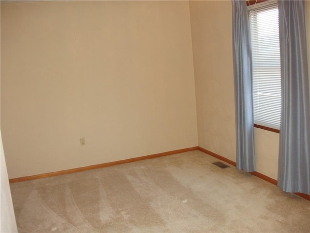 unfurnished room with carpet, visible vents, and baseboards