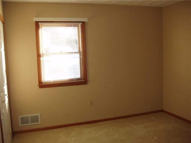 spare room with baseboards, visible vents, and light colored carpet