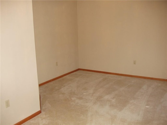 empty room featuring light carpet and baseboards