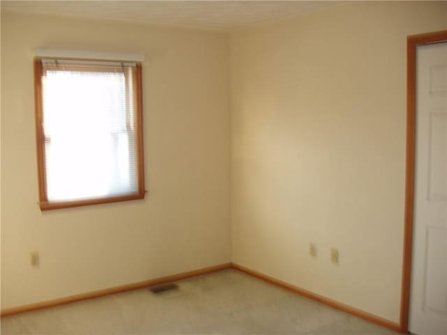 unfurnished room featuring light carpet and baseboards