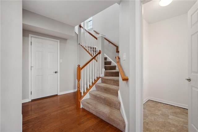 staircase featuring baseboards and wood finished floors