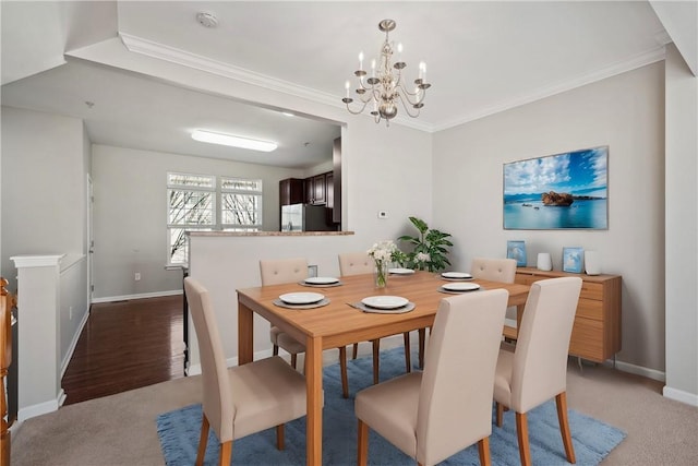 dining area with a notable chandelier, baseboards, crown molding, and light colored carpet